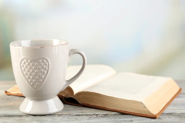 Xícara de chá e livro na mesa, no fundo claro — Fotografia de Stock