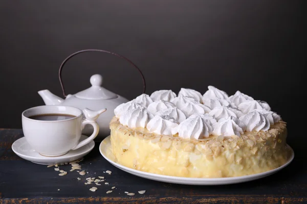 Smakelijk zelfgemaakte meringue taart en kopje thee op houten tafel, op grijze achtergrond — Stockfoto