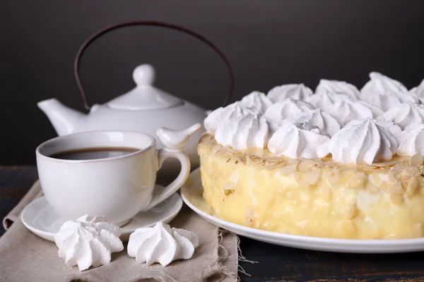 Tasty homemade meringue cake and cup of tea on wooden table, on grey background — Stock Photo, Image