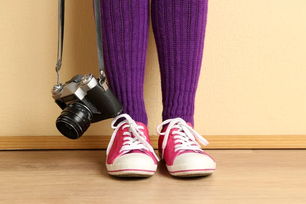 Girl in sneakers with retro photo camera in room — Stock Photo, Image