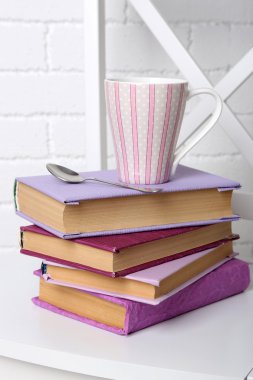 Yığın üzerinde tuğla duvar arka koltuğa bardak ve kaşık ile kitap