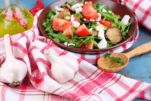 Salada de berinjela com tomate, rúcula e queijo feta, no guardanapo, na cor de fundo de madeira — Fotografia de Stock