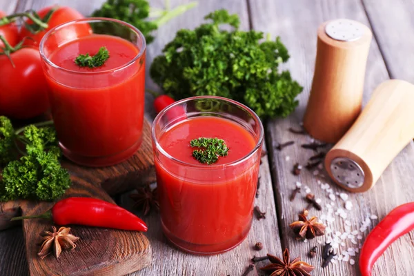 Jugo de tomate en vasos y verduras frescas sobre tabla de cortar sobre fondo de madera —  Fotos de Stock