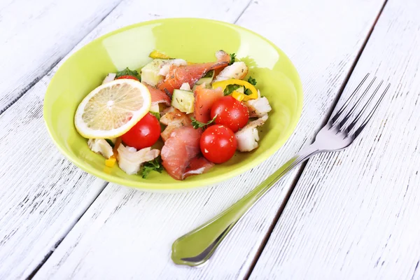 Fresh fish salad with vegetables on plate on wooden table close-up — Stock Photo, Image