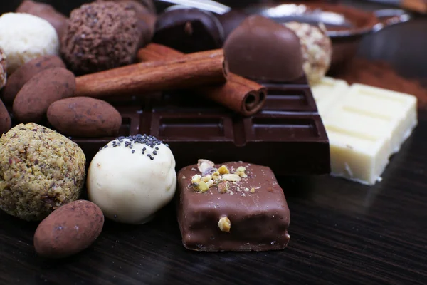 Barras de chocolate y trufas dulces redondas sobre el fondo liso de madera oscura — Foto de Stock