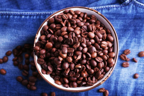 Miska ze zrnkové kávy stojí na pozadí džíny — Stock fotografie