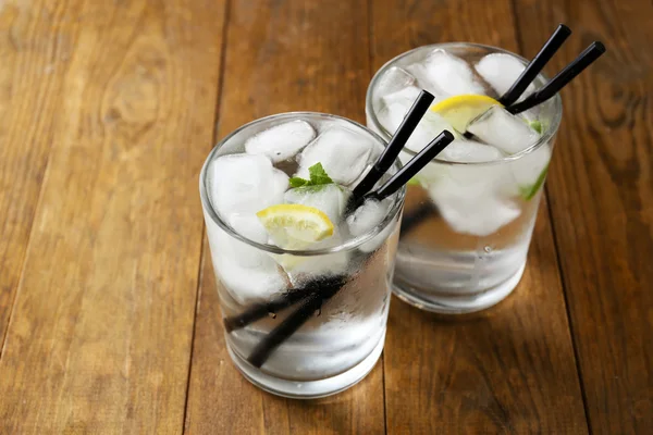 Vaso de agua con cubitos de hielo sobre mesa de madera — Foto de Stock