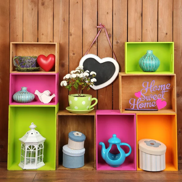 Prachtige kleurrijke planken met verschillende huis verwante objecten op houten muur achtergrond — Stockfoto