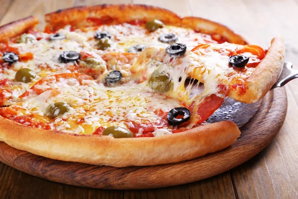 Pizza with cheese on board and wooden table background — Stock Photo, Image