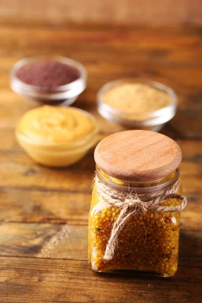 Dijon Mostaza en frasco de vidrio y semillas de mostaza y salsa en cuencos sobre fondo de madera — Foto de Stock