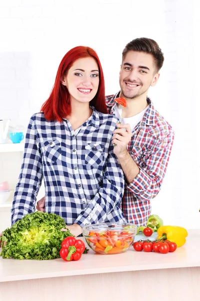 Casal feliz preparando salada de legumes na cozinha — Fotografia de Stock