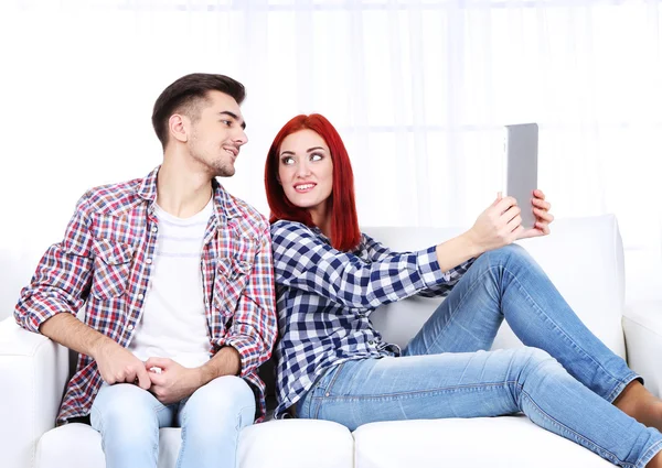 Jeune couple assis dans un canapé avec ordinateur portable dans la chambre — Photo