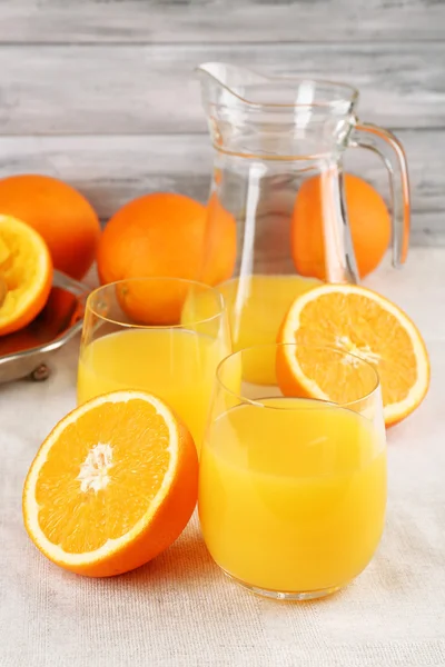 Vaso de jugo de naranja con rodajas en bandeja de metal sobre mesa y fondo de pared de madera de color — Foto de Stock