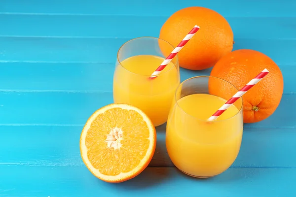 Kieliszek soku pomarańczowego z słomek i plastry na kolor drewniane tła — Zdjęcie stockowe
