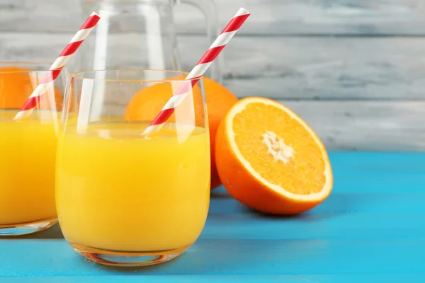 Copo de suco de laranja com palhas e fatias na cor de fundo de madeira — Fotografia de Stock