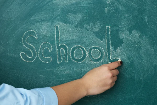 Kvinnlig hand skriver ordet skola på blackboard närbild — Stockfoto