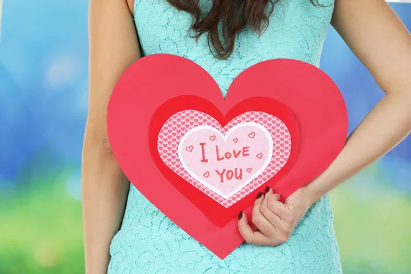 Menina segurando cartão Valentine no fundo brilhante — Fotografia de Stock