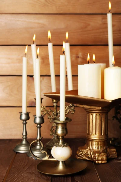 Retro candlesticks with candles on wooden background Royalty Free Stock Images