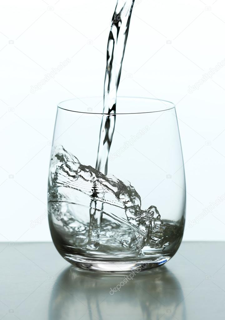 Pouring water from bottle on  glass isolated on white