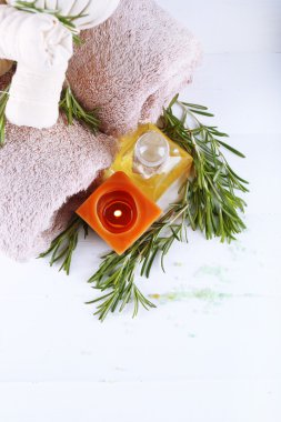 Biberiye ve deniz tuzu, havlu, mum ve masaj yağı renk ahşap arka plan üzerinde şişeyle dallarında. Biberiye spa konsept