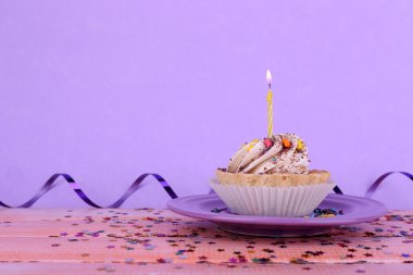 Doğum günü kek ile mum ile renk ahşap masa ve açık renkli plaka üzerinde parıldıyor