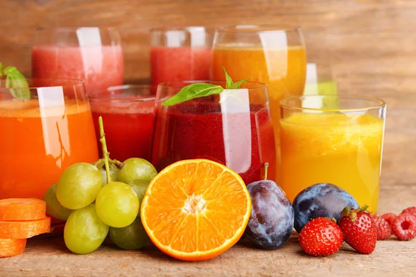 Gläser mit leckerem frischen Saft, auf Holztisch. — Stockfoto