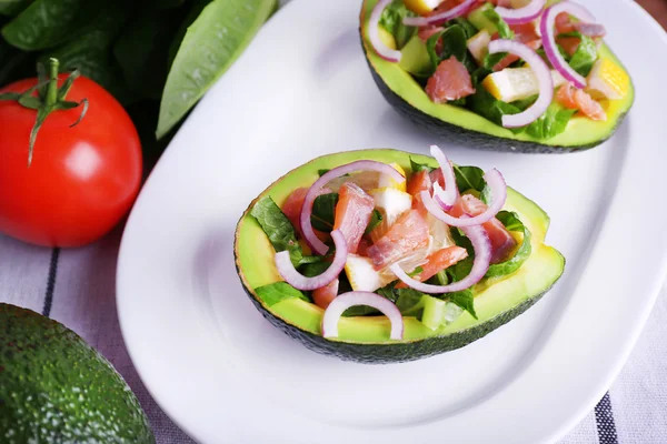 Smakfull salat i avokado på tallerkenbordet. – stockfoto