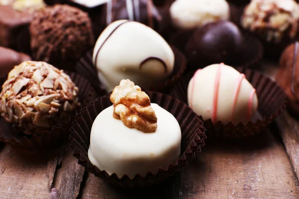Many chocolates on wooden textured background — Stock Photo, Image