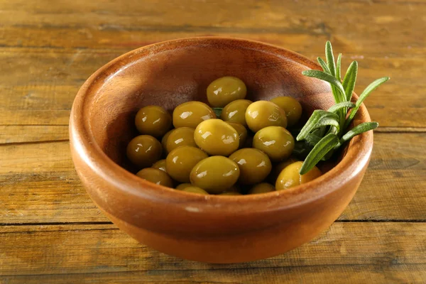 Gröna oliver i runda skålen med gren på rustika trä bakgrund — Stockfoto