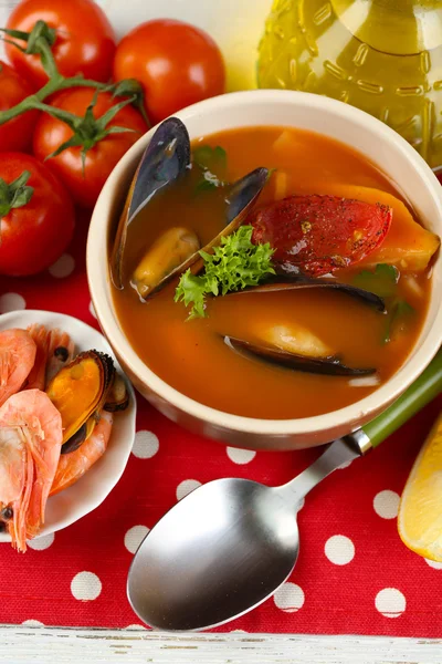 Tasty soup with shrimps, mussels, tomatoes and black olives in bowl on wooden background — Stock Photo, Image