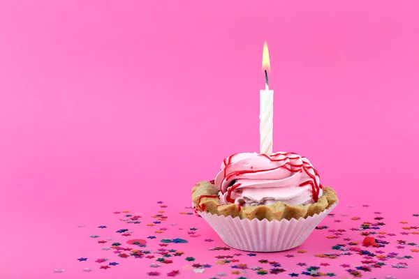 Gâteau d'anniversaire avec bougie et étoiles colorées sur fond rose — Photo