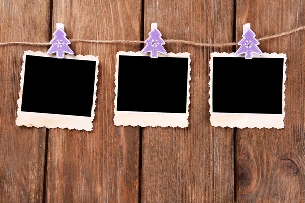 Blank photo frames and Christmas decor on rope, on wooden background — Stock Photo, Image
