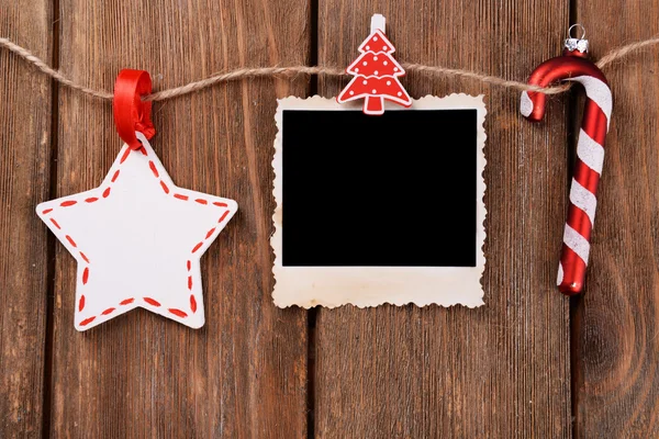 Leeg fotokader en Christmas decor op touw, op houten achtergrond — Stockfoto