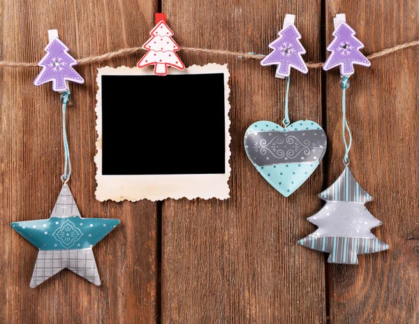 Blank photo frame and Christmas decor on rope, on wooden background — Stock Photo, Image