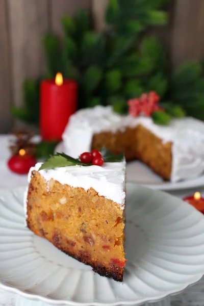 Rebanada de crema cubierta de pastel con decoración de Navidad en la mesa, sobre fondo de pared de madera — Foto de Stock