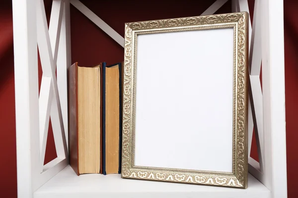 Photo frame with books on shelf, on color wall background — Stock Photo, Image