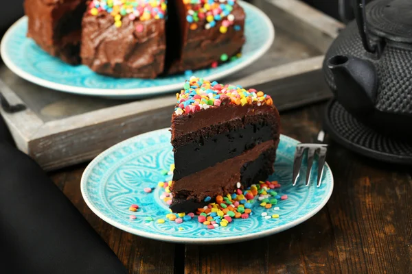 Gâteau au chocolat avec poudre sucrée colorée sur la table close-up — Photo