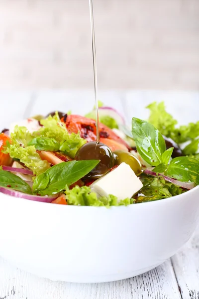 Griechischer Salat im Teller auf farbigem Holztischhintergrund — Stockfoto