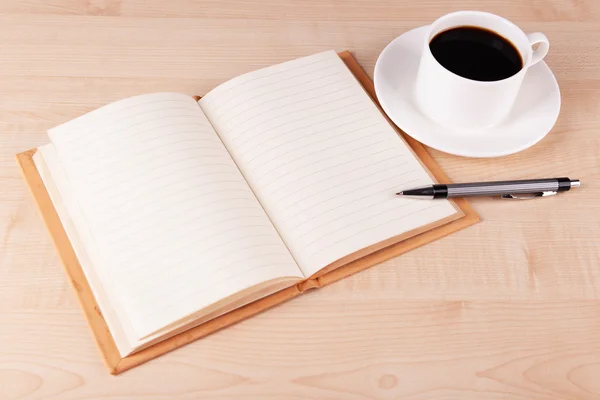 Taza de café en platillo con cuaderno abierto y pluma sobre fondo de mesa de madera — Foto de Stock