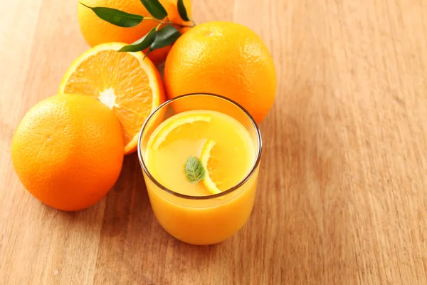 Vaso de zumo de naranja con rodajas sobre fondo de mesa de madera — Foto de Stock