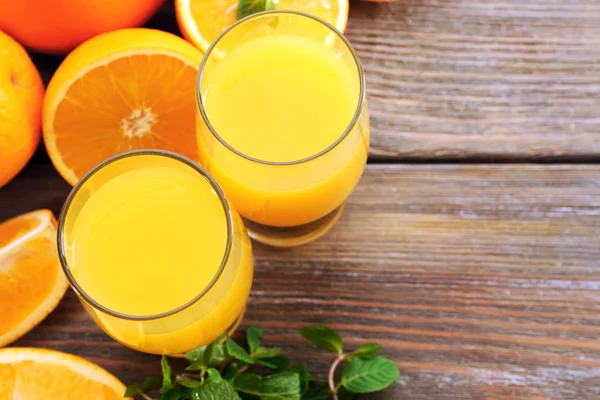 Copo de suco de laranja e fatias em fundo de mesa de madeira — Fotografia de Stock