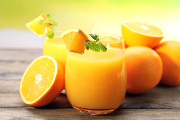 Copo de suco de laranja e fatias em fundo de mesa de madeira — Fotografia de Stock