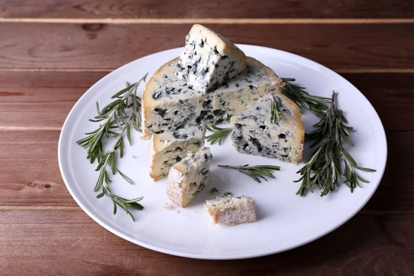 접시와 나무 테이블 배경에 로즈마리의 sprigs와 블루 치즈 — 스톡 사진