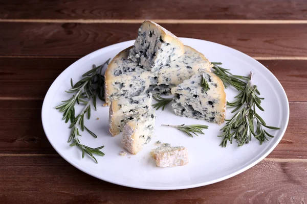 Kék sajt és sprigs a rozmaring, a lemez és a fából készült asztal háttere — Stock Fotó