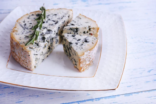 Blue cheese with sprigs of rosemary on plate and color wooden table background — Stock Photo, Image