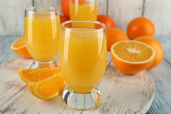 木の色の背景上のスライスでのオレンジ ジュースのガラス — ストック写真
