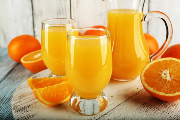 Glass of orange juice with slices on color wooden background — Stock Photo, Image