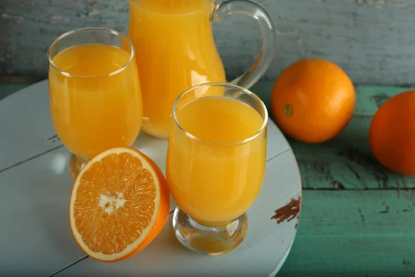 Glass of orange juice with slices on color wooden background — Stock Photo, Image