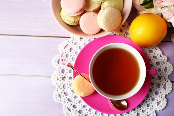 Macarrones coloridos con taza de té sobre fondo de madera — Foto de Stock