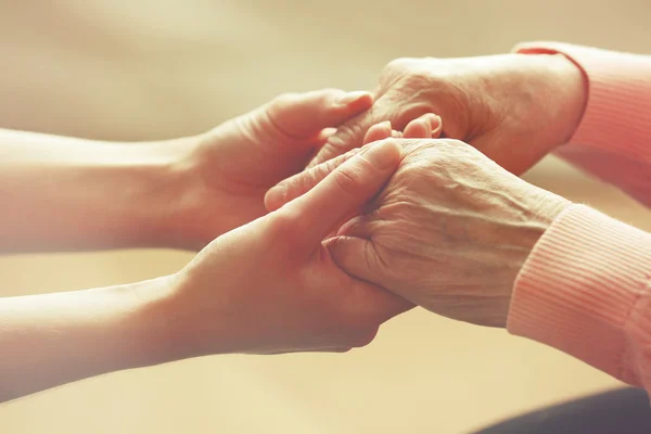 Vecchi e giovani che si tengono per mano su sfondo chiaro, primo piano — Foto Stock